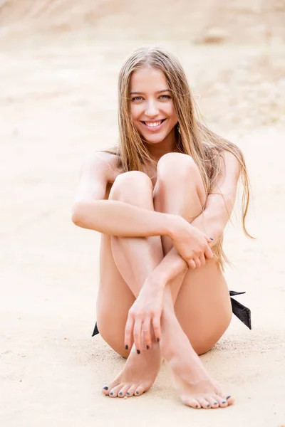 Ragazza con bella pelle in posa seduta sulla sabbia in bikini — Foto Stock