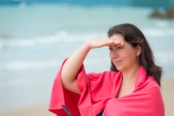 Chica morena en una toalla rosa en la playa por la mañana —  Fotos de Stock