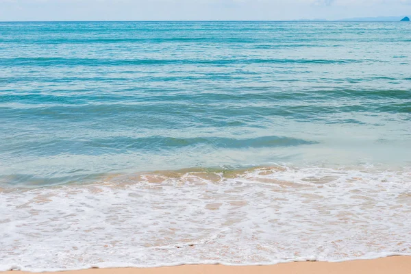 Eau de mer turquoise et vagues de mousse blanche sur une plage de sable — Photo