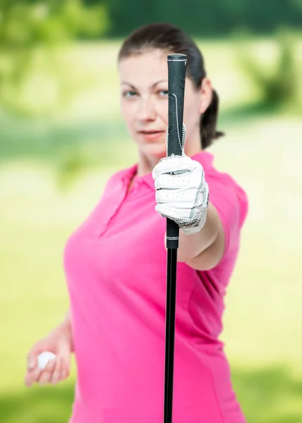 Atleet toont een golf club op de camera op een achtergrond van golf — Stockfoto