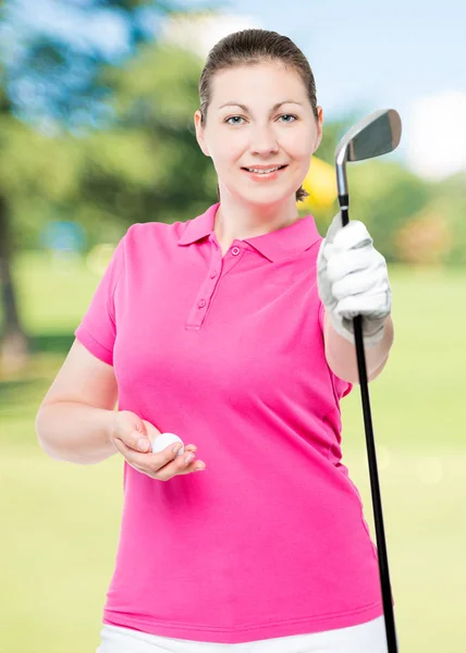 Woman golfer holding a stick and a ball on a background of golf