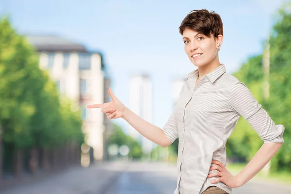 Brunette in een gestreepte shirt toont zijn vinger op de ruimte links — Stockfoto