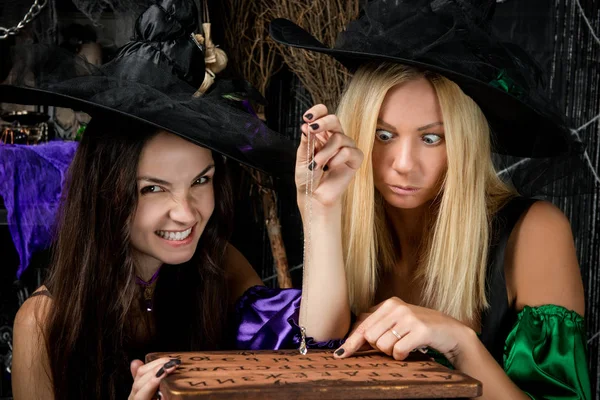 Очаровательные молодые ведьмы с доской догадок — стоковое фото
