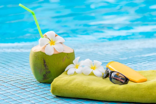 Green towel and beach accessories near to a juicy coconut decora — Stock Photo, Image