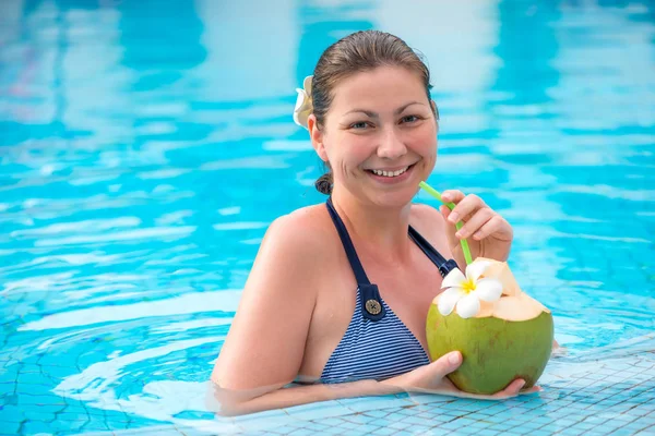 Portrait d'une femme avec une noix de coco reposant dans une piscine dans la trop — Photo