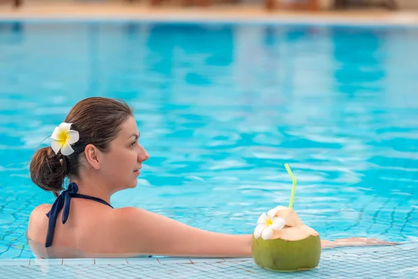 Horizontal frame - portrait of a girl in a pool with a coconut — Stock Photo, Image