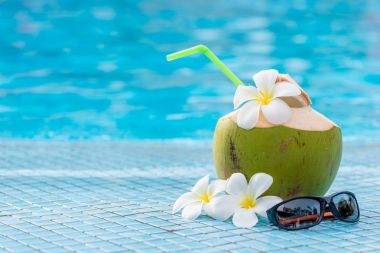 Havuzun kenarındaki mavi bir kutu üzerindeki sütlü yeşil Hindistan cevizi