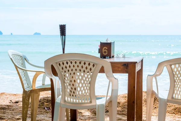 Empty table on the beach in the shade of a tree — Stock Photo, Image