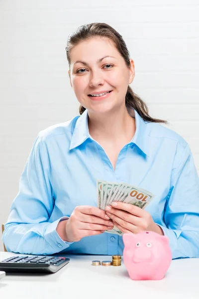 A girl with a calculator, money and a piggy bank will count the — Stock Photo, Image