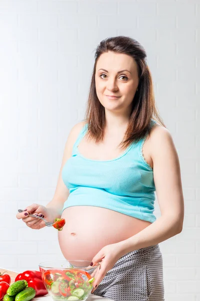 Brünette werdende Mutter mit nützlichen Lebensmitteln in der Küche — Stockfoto