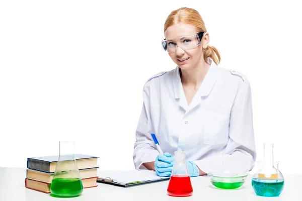 Smiling young chemist at a table with test tubes — Stock Photo, Image