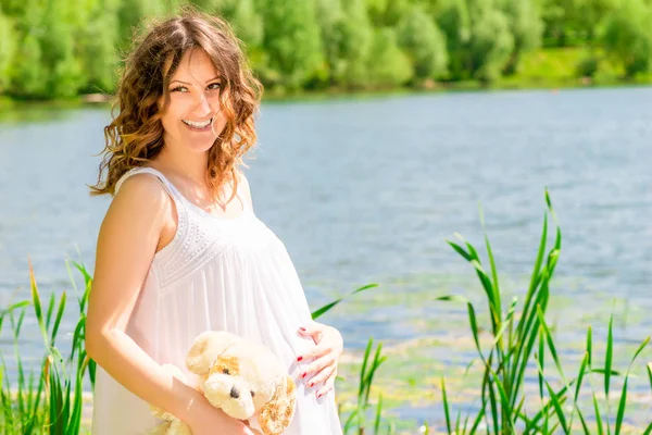 Mujer embarazada feliz posando en la naturaleza cerca del lago — Foto de Stock