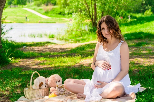 Zwangere mooie vrouw in witte kleren, rustend op een picknick in — Stockfoto