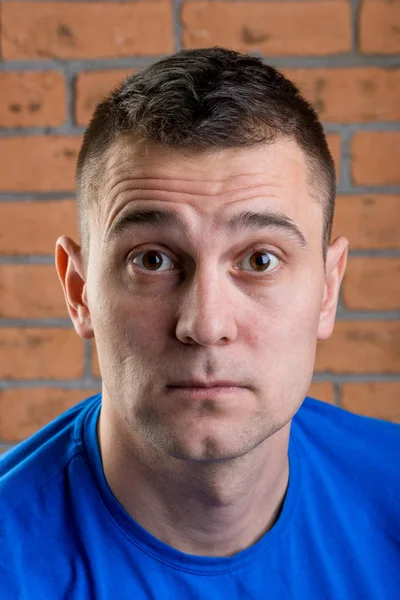 Portrait of a man with surprise on his face against a brick wall — Stock Photo, Image