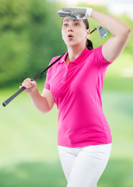 Atleta mulher assistindo a bola voo caminho de golfe em um backgro — Fotografia de Stock