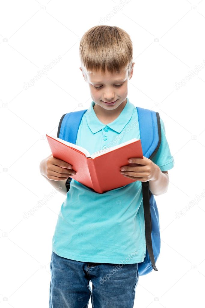 portrait of a boy reading a book, behind his backpack on a white