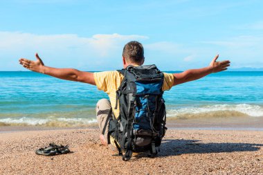 bir turist kolları yanlara yayılmış olan bir sırt çantası ile oturur