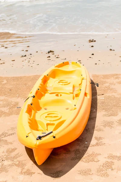Kayak de plástico amarillo se encuentra en una playa de arena cerca del mar —  Fotos de Stock