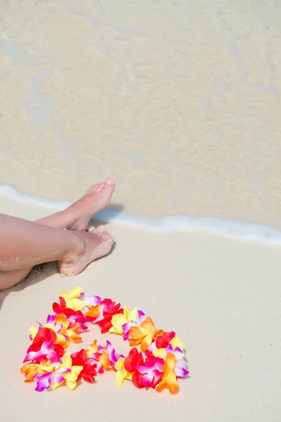 Beautiful legs and Hawaiian floral lei near the sea on white gen — Stock Photo, Image