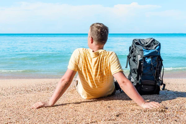 Ontspannen toerist met een rugzak in de buurt van de zee op het strand — Stockfoto