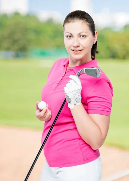 Young brunette loves to play golf, posing on a background of gol — Stock Photo, Image