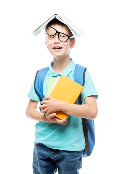 Garçon ludique dans des lunettes avec livre sur la tête posant contre ba blanc — Photo