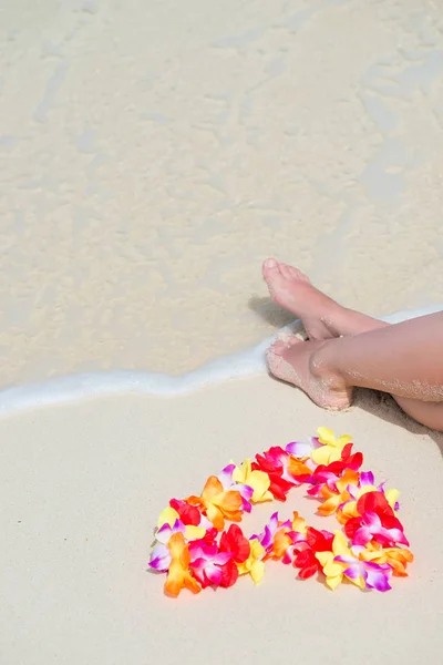 Meereswelle, weibliche Füße und hawaiianische Blumenperlen auf dem Ozean sho — Stockfoto