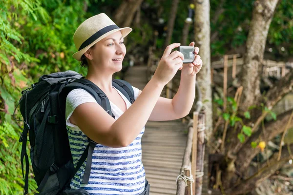 Mujer con una mochila fotos hermosas vistas en el teléfono — Foto de Stock