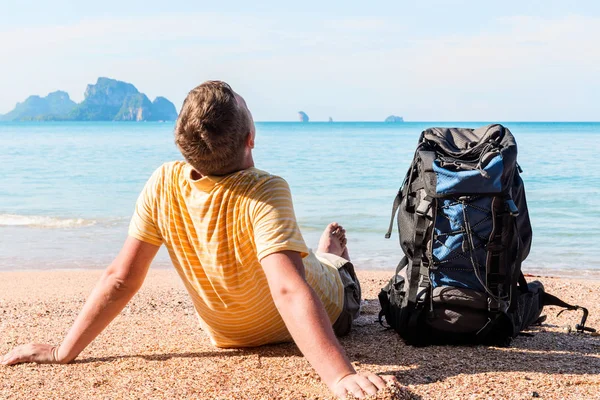 Turist med en stor ryggsäck slappnar på stranden nära havet — Stockfoto