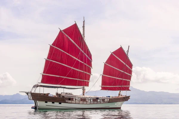 An authentic yacht with red sails in the sea against the backdro — Stock Photo, Image