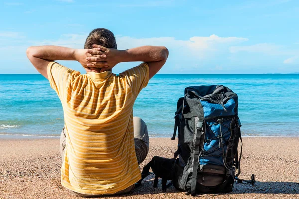 Mann Tourist mit Rucksack blickt auf die schöne ruhige See auf — Stockfoto