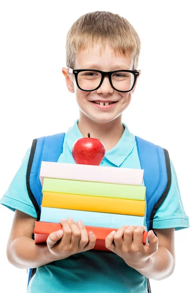 Écolier souriant avec des lunettes avec une pile de livres et un rouge — Photo