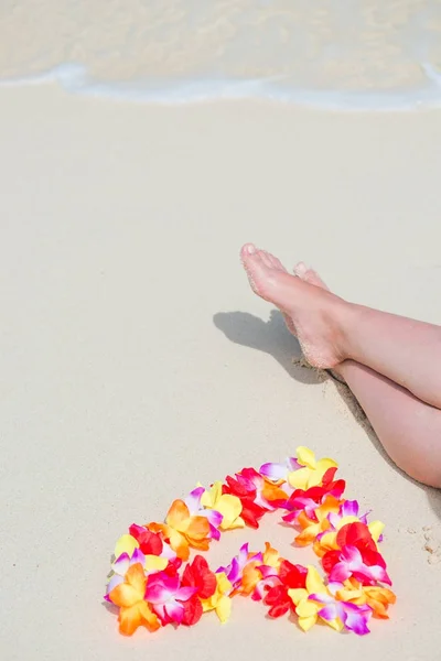 Гавайские бусины в форме сердца возле женских ног на т — стоковое фото