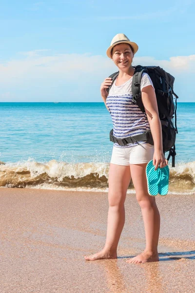 Vertical portrait of a tourist with a backpack on the shore of a — Stock Photo, Image