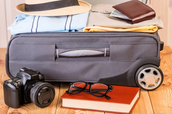 Una cámara y un libro con gafas cerca de una maleta abierta son andar —  Fotos de Stock