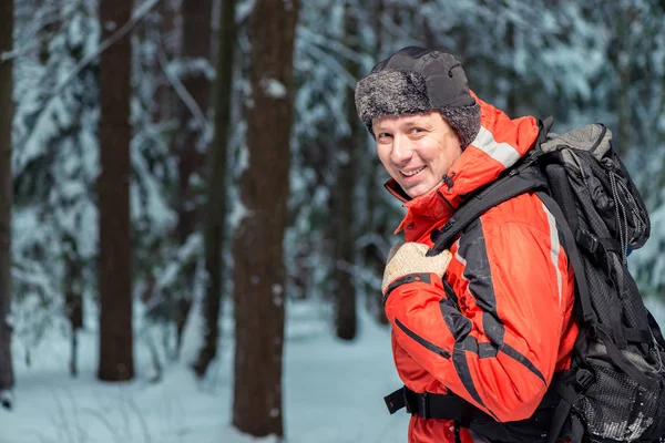 Turista feliz em uma jaqueta em uma caminhada com uma mochila no winte — Fotografia de Stock