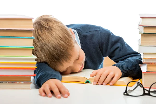 Skolpojke sover vid ett bord mellan högar av böcker på en whi — Stockfoto