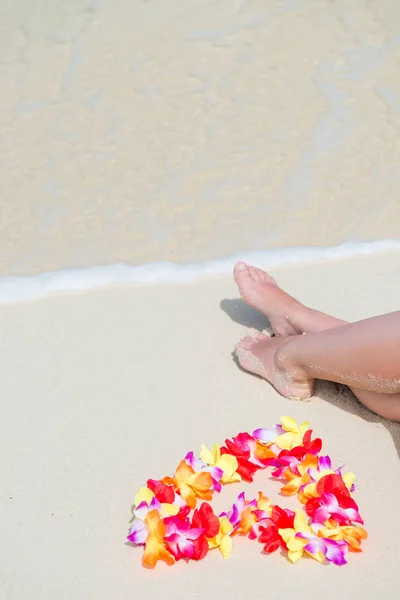 女性の足の近くのハートの形をした花のハワイアン レイ — ストック写真