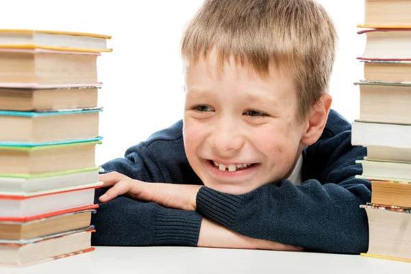 Portrait of a laughing schoolboy close-up among a pile of books — Stock Photo, Image