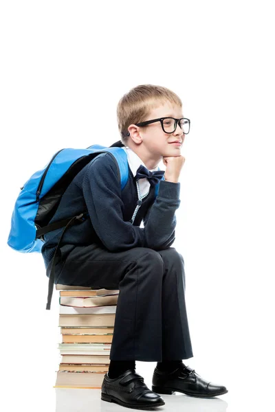 Thoughtful schoolboy sitting on a pile of books on a white backg — Stock Photo, Image