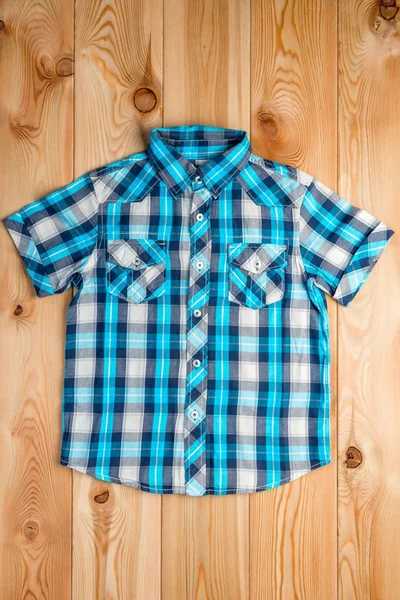 Blue checkered shirt for a boy in a rural style on the wooden fl — Stock Photo, Image