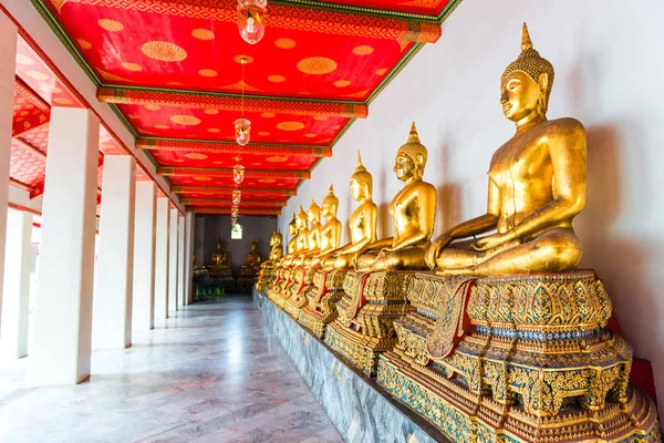 Eine Statue eines sitzenden Buddhas an einer Wand in einem Tempel in einer Reihe — Stockfoto