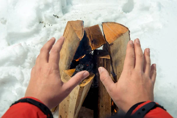 Nahaufnahme-Foto - Tourist wärmt seine Hände am Feuer im Wald — Stockfoto