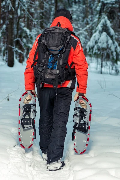 Turista cansado carrega sapatos de neve em suas mãos no inverno para — Fotografia de Stock