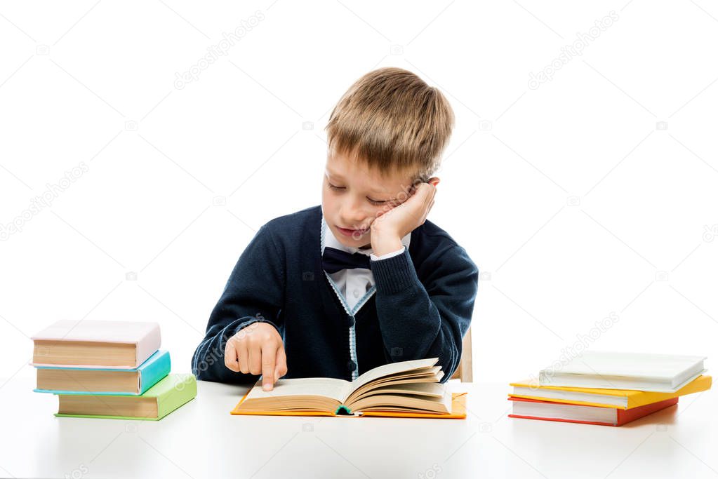 8-year-old schoolboy reading a book at a table, portrait isolate