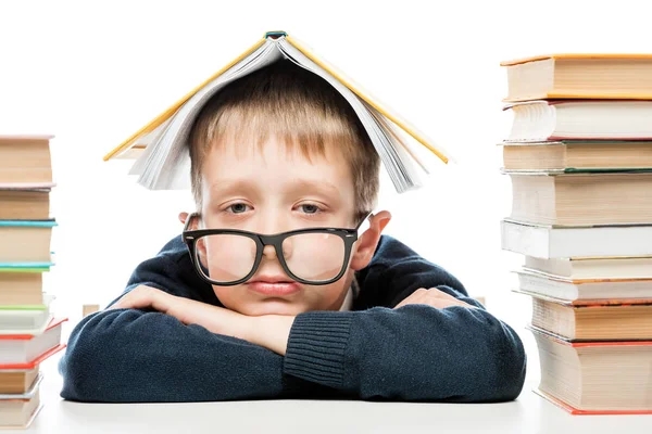 Portrait of a tired schoolboy wearing glasses with a book on his — Stock Photo, Image