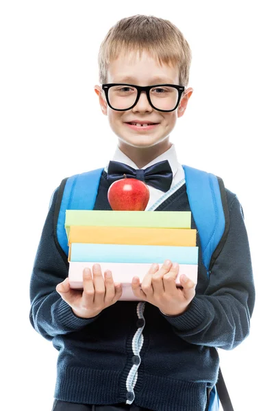 Glimlachend scholier met een bril met een stapel boeken in handen p — Stockfoto