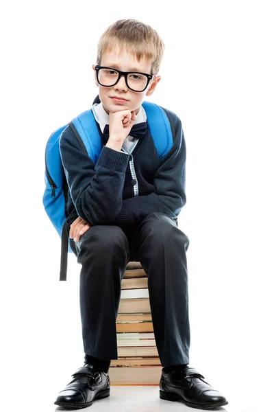 Portrait of a schoolboy with glasses sitting on a pile of books — Stock Photo, Image