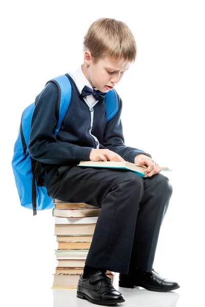 The student is sitting on a pile of books and reads a textbook o — Stock Photo, Image