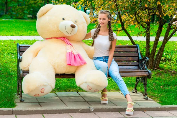 Porträt eines glücklichen Mädchens auf einer Bank mit deiner Lieblings-Teddybea — Stockfoto